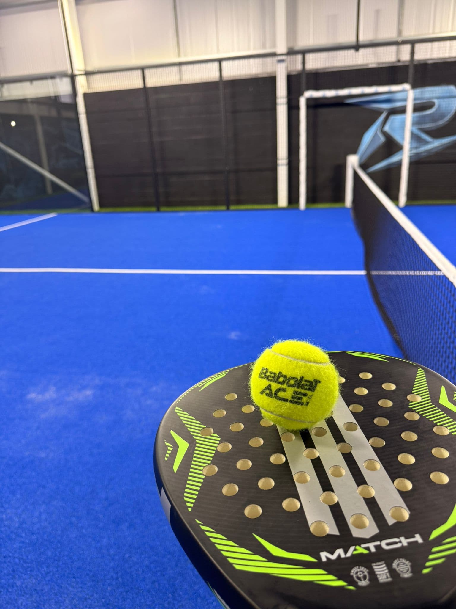 Padel racket and ball on a RAZR Padel court